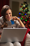 Smiling young woman with laptop and credit card near christmas t