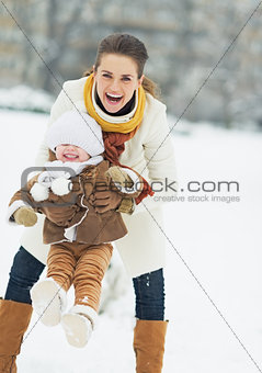 Happy mother playing with baby in winter park