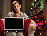 Smiling young woman showing laptop blank screen