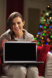 Happy young woman showing laptop blank screen