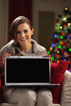 Happy young woman showing laptop blank screen
