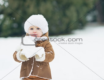 Baby playing with snow in winter park