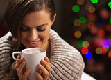 Happy woman with cup of hot chocolate with marshmallow in front 