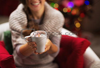 Closeup on cup of hot chocolate with marshmallow in hand of smil