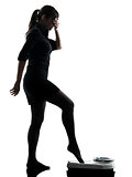 anxious woman standing on weight scale  silhouette