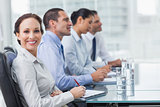 Businesswoman smiling at camera while her colleagues listening to presentation
