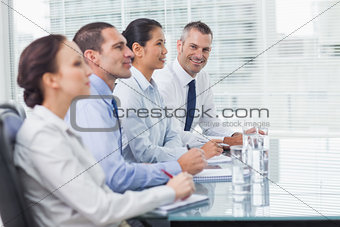 Businessman smiling at camera while his colleagues listening