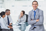 Smiling businessman posing while workmates talking together