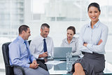 Smiling businesswoman posing while workmates talking together