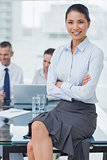 Smiling businesswoman posing with workmates on background