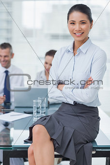 Smiling businesswoman posing with workmates on background