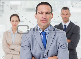 Serious employee posing with his colleagues on background