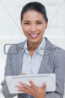 Smiling businesswoman posing scrolling on her tablet pc