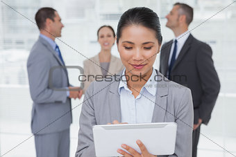 Businesswoman with her tablet pc while colleagues talking together