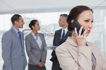 Businesswoman on the phone while colleagues talking together