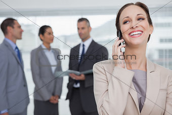Cheerful businesswoman calling while colleagues talking together