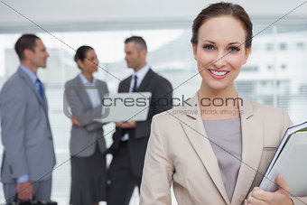 Cheerful businesswoman holding files smiling at camera