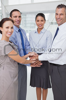 Smiling work team joining hands together