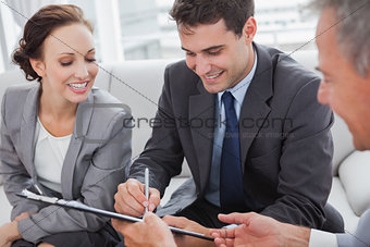 Businessman signing contract while his partner is looking at him