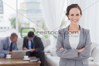 Cheerful businesswoman posing while her colleagues are working