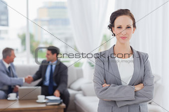 Content businesswoman posing while her colleagues are working