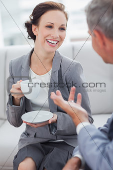 Cheerful businesswoman having coffee with her workmate