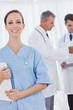 Cheerful surgeon posing while doctors talking on background