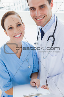 Smiling doctor and surgeon posing while holding documents together