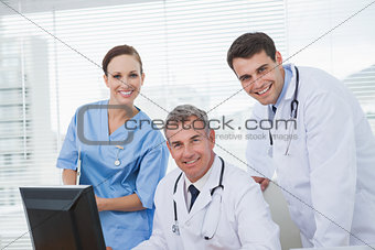 Cheerful doctors and surgeon looking at camera while working together