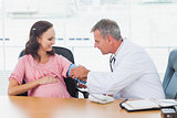 Doctor taking blood pressure of pregnant patient