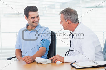 Doctor taking blood pressure of smiling patient