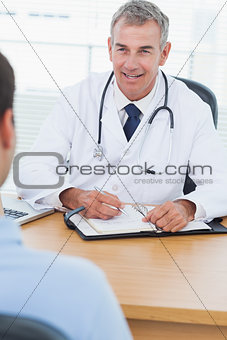 Cheerful doctor prescribing drug to his patient