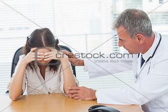 Serious doctor comforting his patient after telling her diagnosis