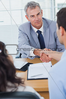 Serious real estate agent shaking hands with his new buyer