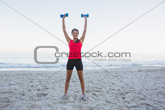 Cheerful sporty woman holding dumbbells