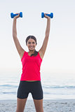 Smiling sporty woman holding dumbbells