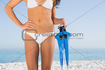 Perfect female body in white bikini holding fins