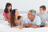 Smiling family talking together on bed