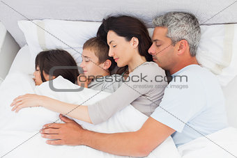 Smiling family sleeping together in bed