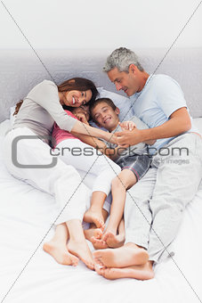 Smiling family lying on bed