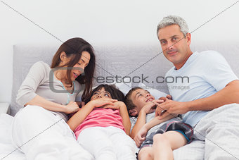 Cheerful family lying on bed
