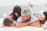 Cute family lying on bed and talking together