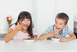 Siblings eating cereal for breakfast in kitchen