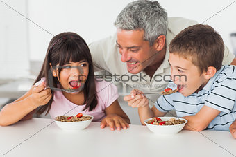 Smiling father talking with his children during their breakfast