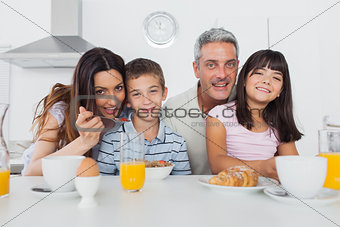 Cheerful family eating breakfast in kitchen together