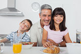 Siblings eating breakfast in kitchen together with dad