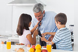 Children fixing their fathers tie in the kitchen
