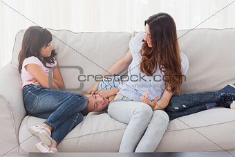 Little boy lying on sofa with his mother and sister