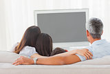 Family watching television together on sofa