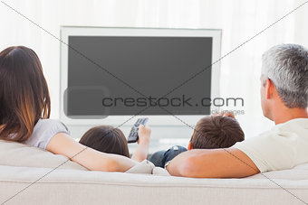 Family sitting on sofa watching television together